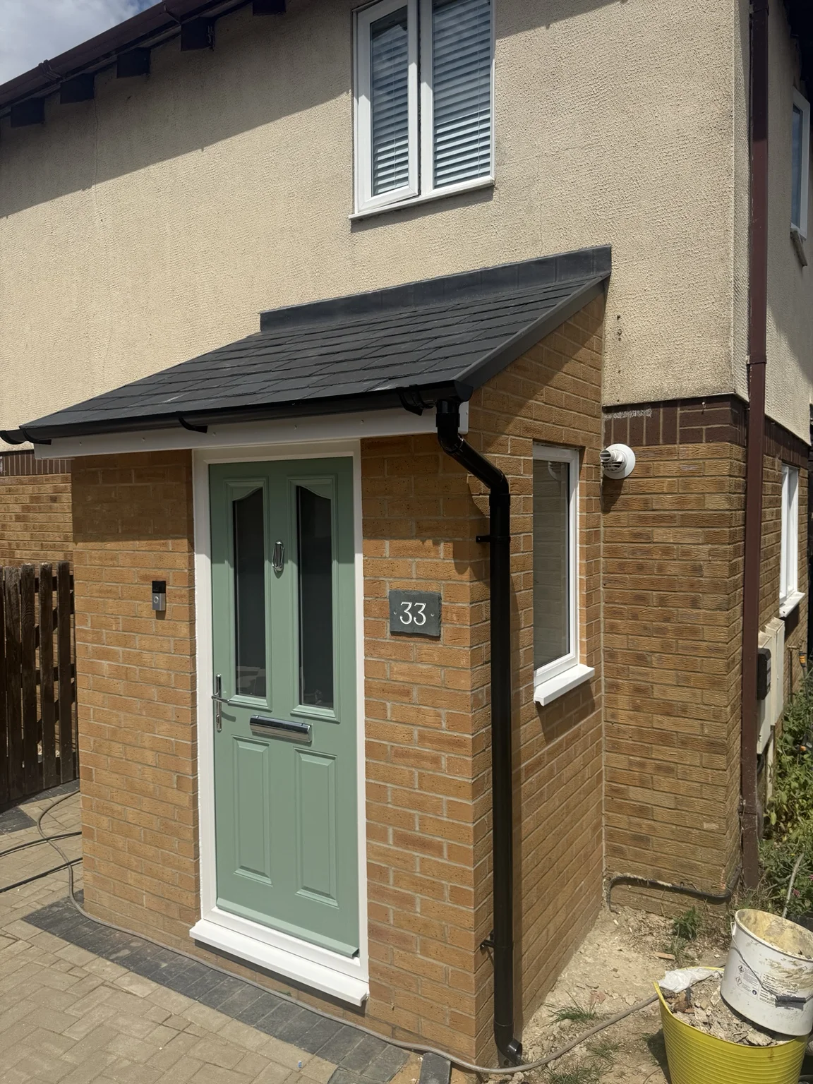 Green front door beneath a pitched entrance canopy